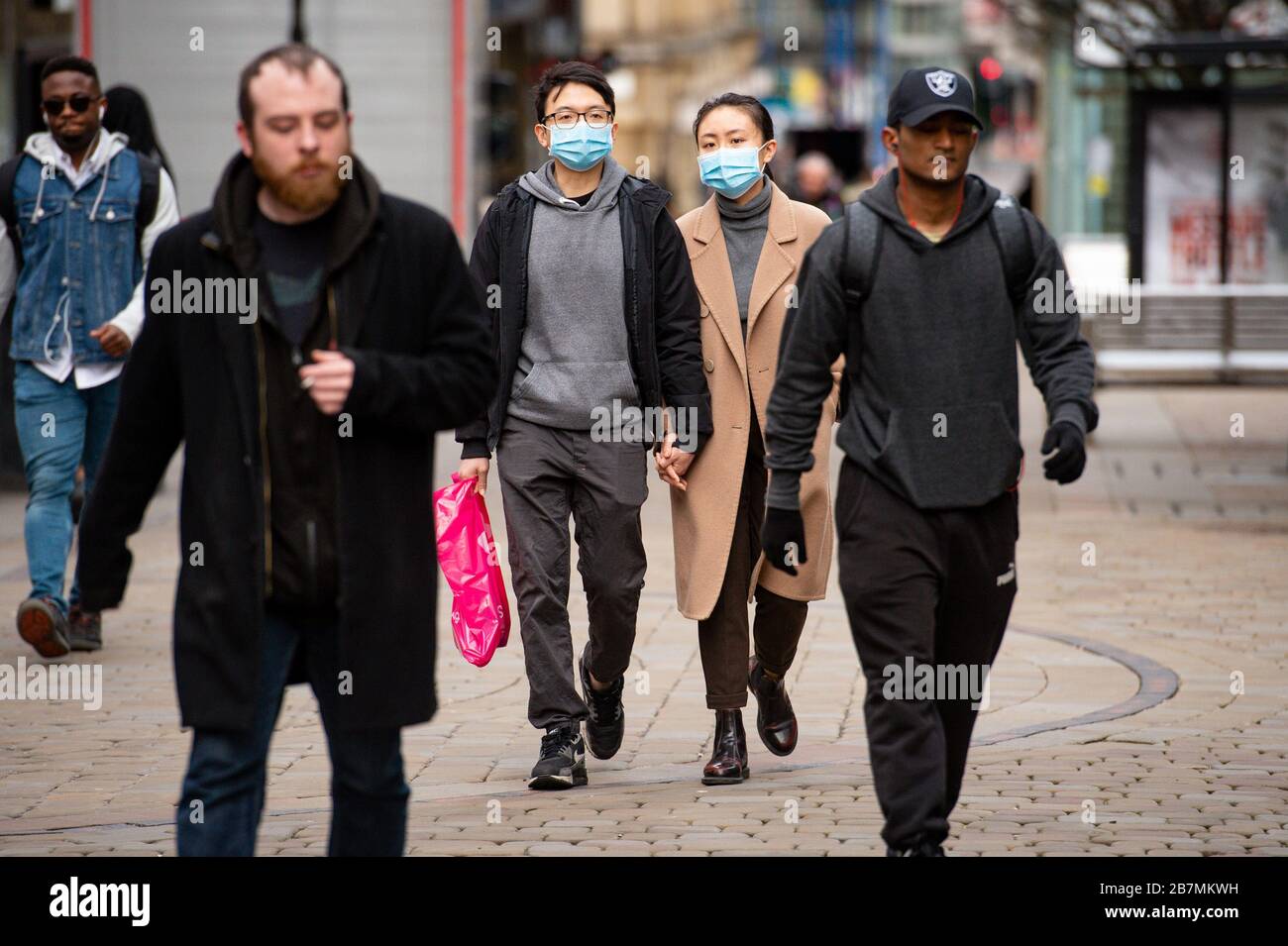 People wearing protective masks in Manchester, the day after Prime Minister Boris Johnson called on people to stay away from pubs, clubs and theatres, work from home if possible and avoid all non-essential contacts and travel in order to reduce the impact of the coronavirus pandemic. Stock Photo