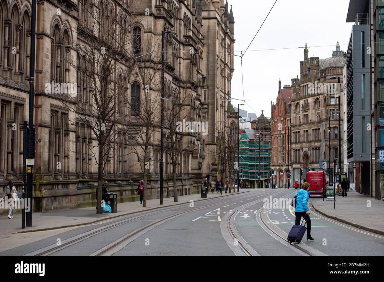 A woman walks across Princess Street in Manchester city centre, the day after Prime Minister Boris Johnson called on people to stay away from pubs, clubs and theatres, work from home if possible and avoid all non-essential contacts and travel in order to reduce the impact of the coronavirus pandemic. Stock Photo