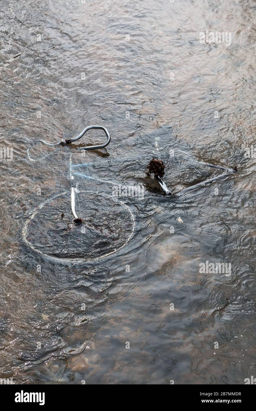 Steel bicycle strown into the river is pollution for environment Stock Photo