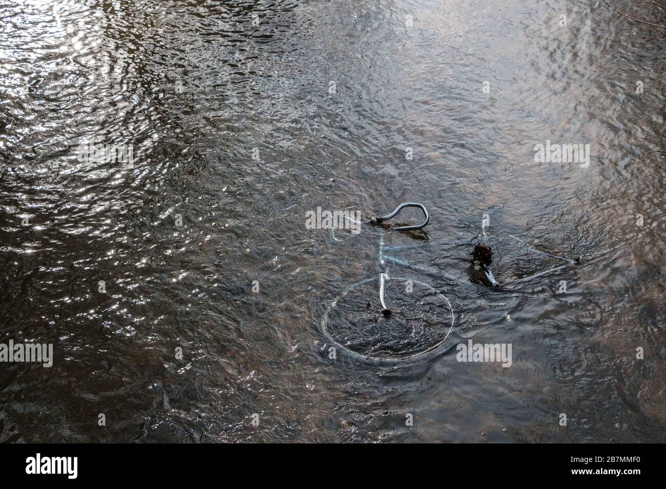 Steel bicycle strown into the river is pollution for environment Stock Photo