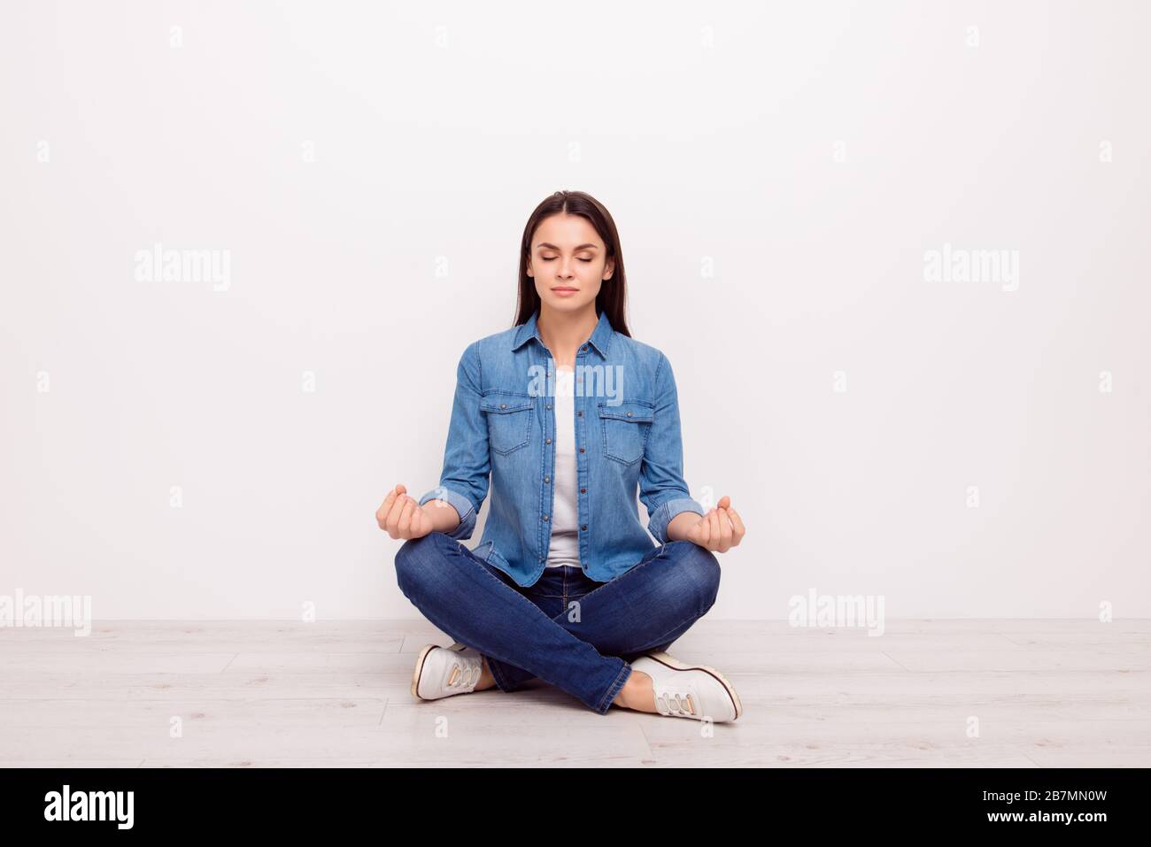 Photo of concentrated woman gesturing om sign sitting on floor and meditating Stock Photo