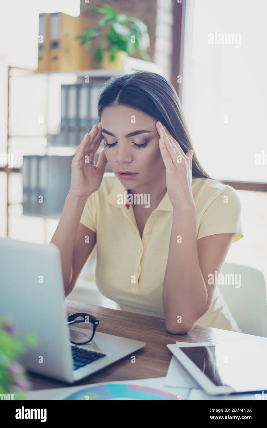 Close up portrait of a young pretty woman having headache after stressful workday and touching her temples Stock Photo