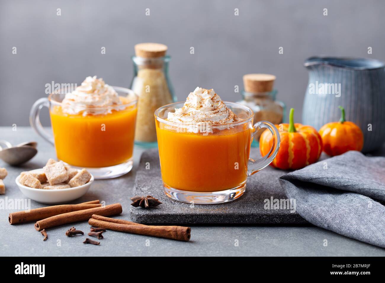 Pumpkin latte with whipped cream in glass cups. Grey background. Close up. Stock Photo