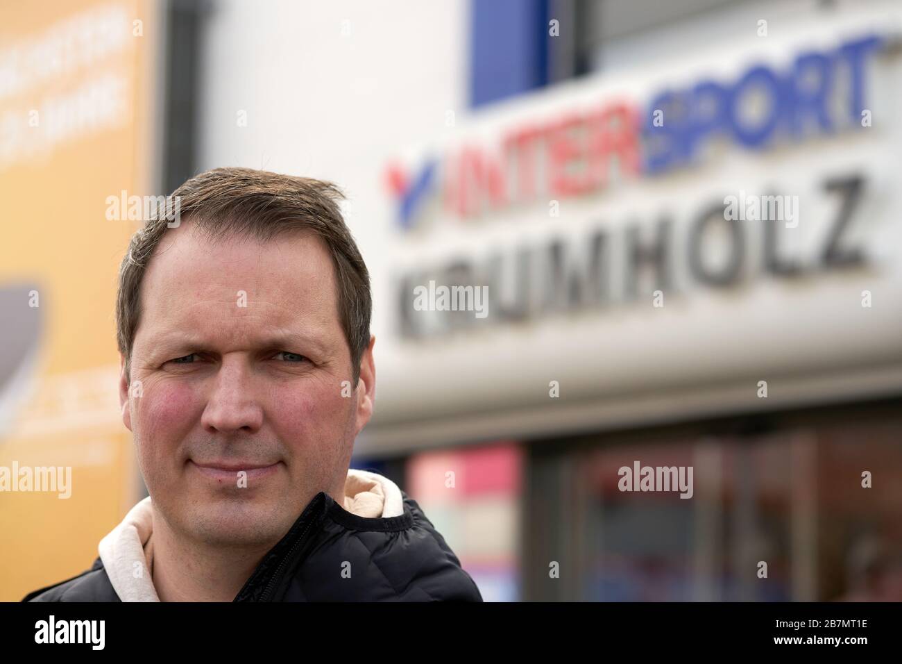 17 March 2020, Rhineland-Palatinate, Mülheim-Kärlich: Oliver Krumholz, managing director of the sports shop Intersport Krumholz, is standing in front of the entrance to his shop. Starting tomorrow, most of the shops that do not serve daily needs will be closed. Photo: Thomas Frey/dpa Stock Photo