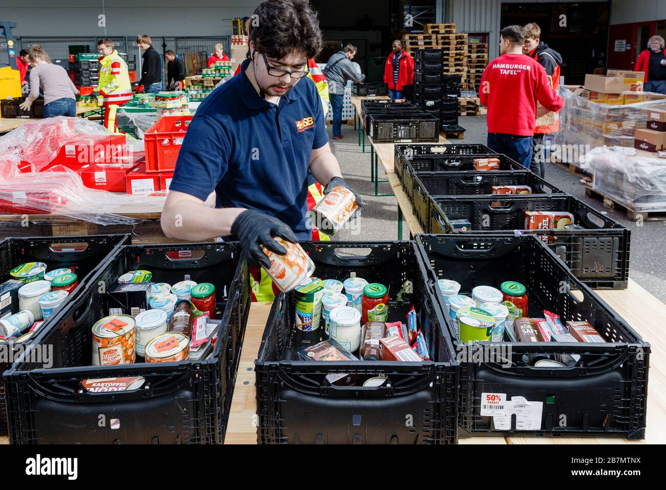 17 March 2020, Hamburg: Voluntary helpers from the Hamburger Tafel and the  Arbeiter-Samariter-Bund are packing boxes of food for the distribution  points of the Tafel in the central depot. The distribution of