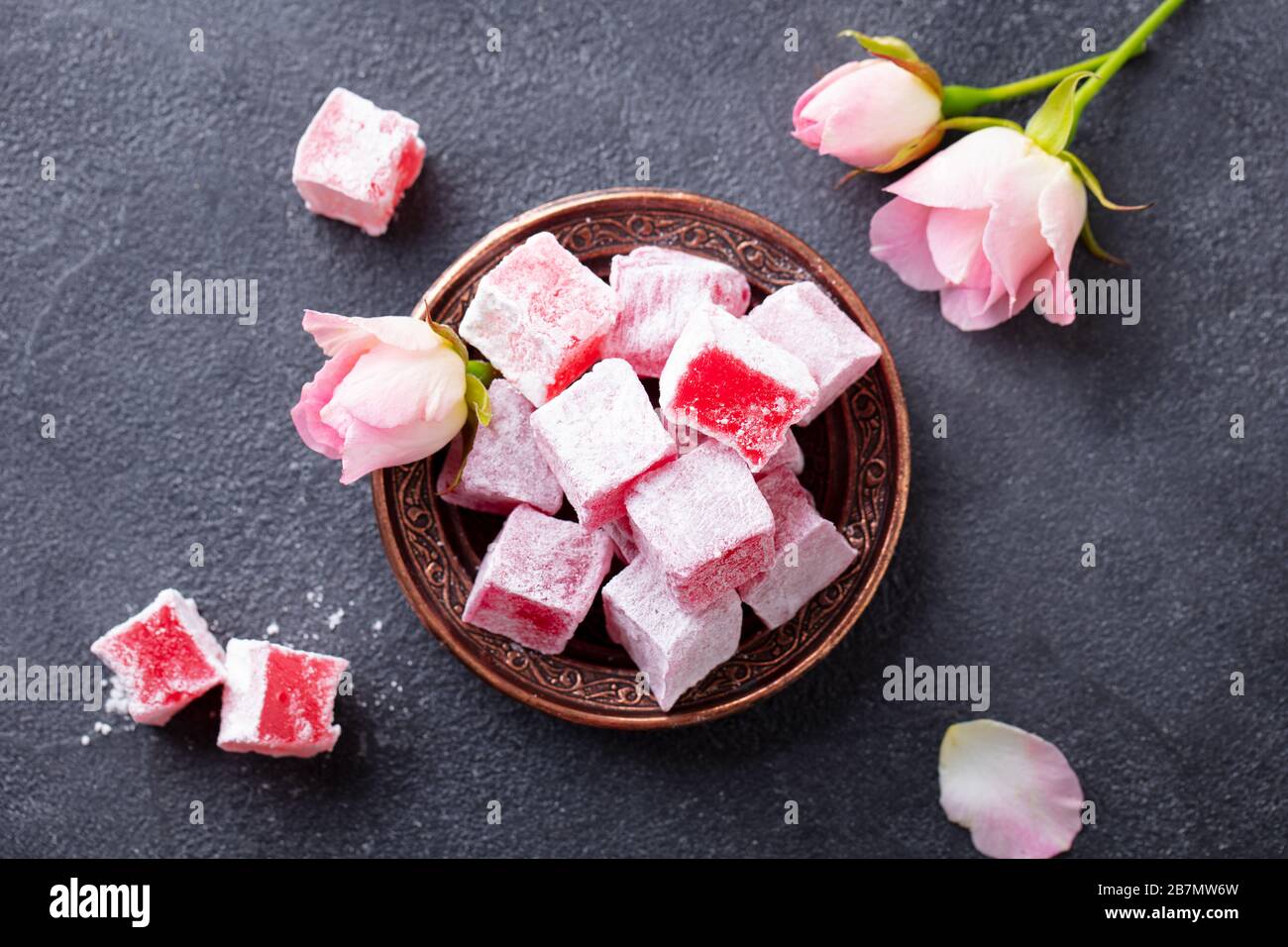 Turkish delights lokum, rose flavour in a copper plate. Dark background. Top view. Stock Photo