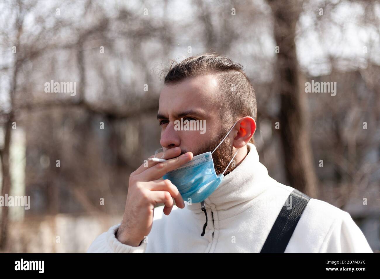 Man with face mask smoking cigarette hires stock photography and