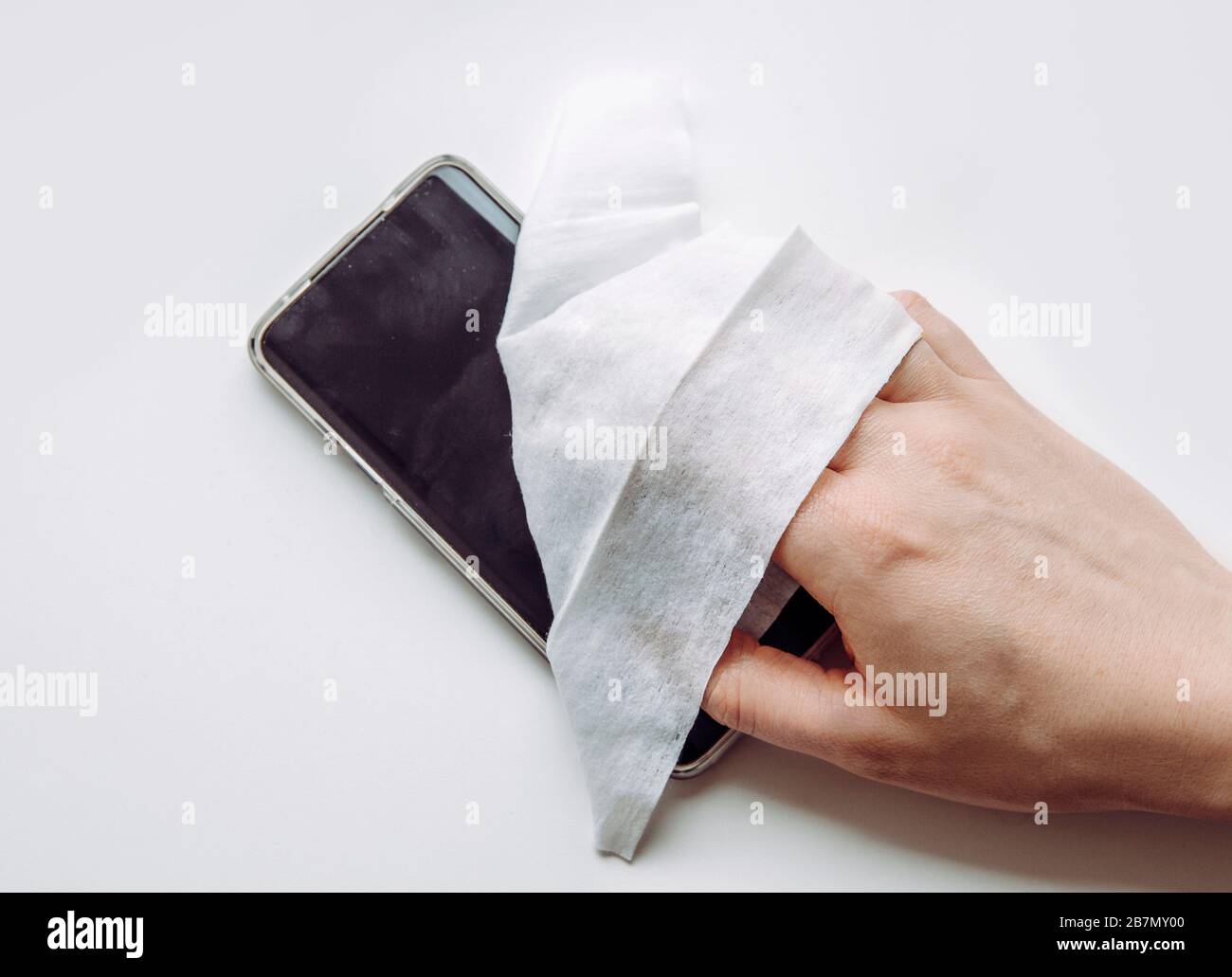 Close up view of man hand using antibacterial wet wipe for disinfecting smartphone touch screen. Stock Photo