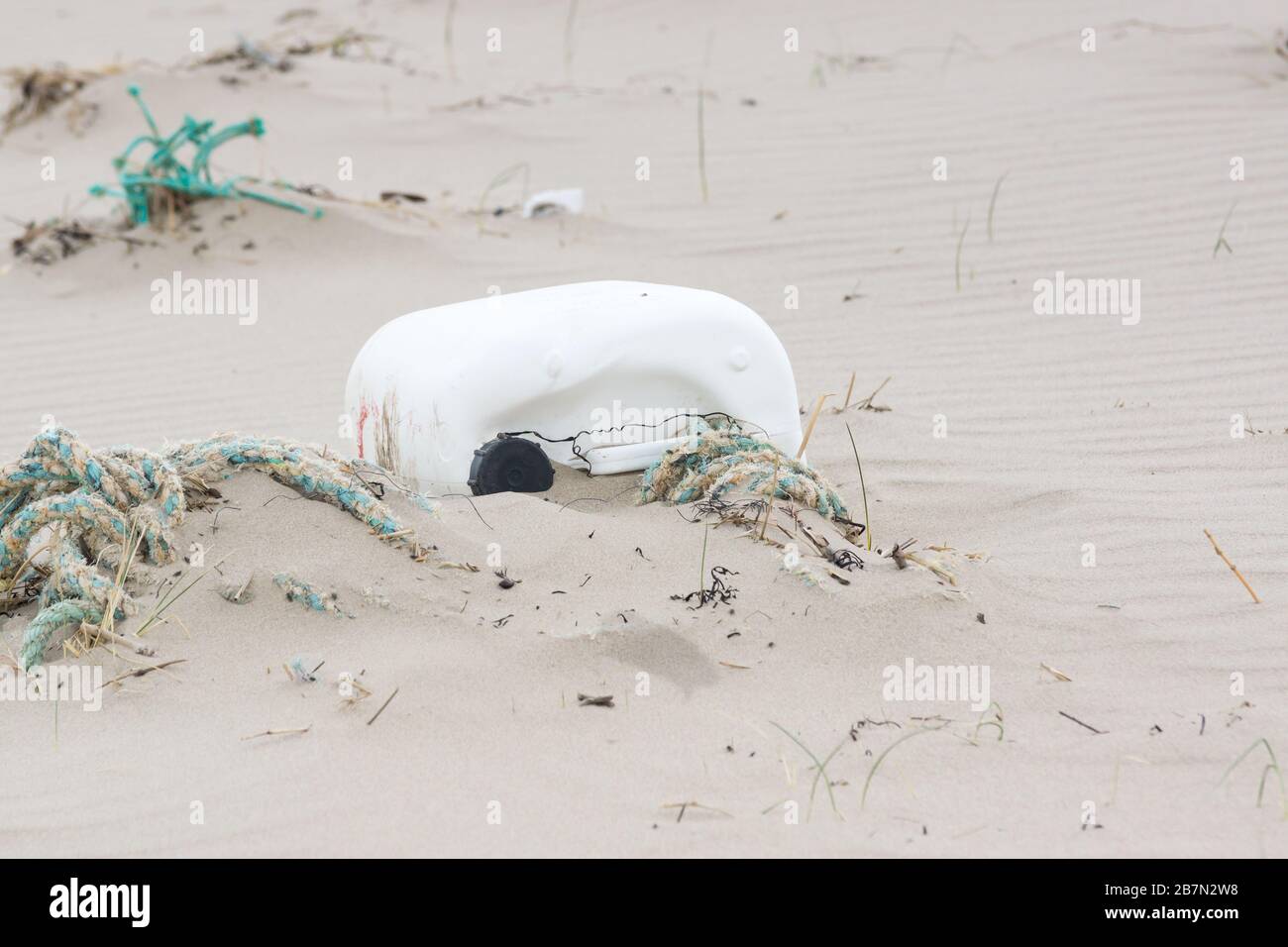 Plastic container and rope washed up on a beach in Harlech UK an example of the environmental pollution in the sea Stock Photo