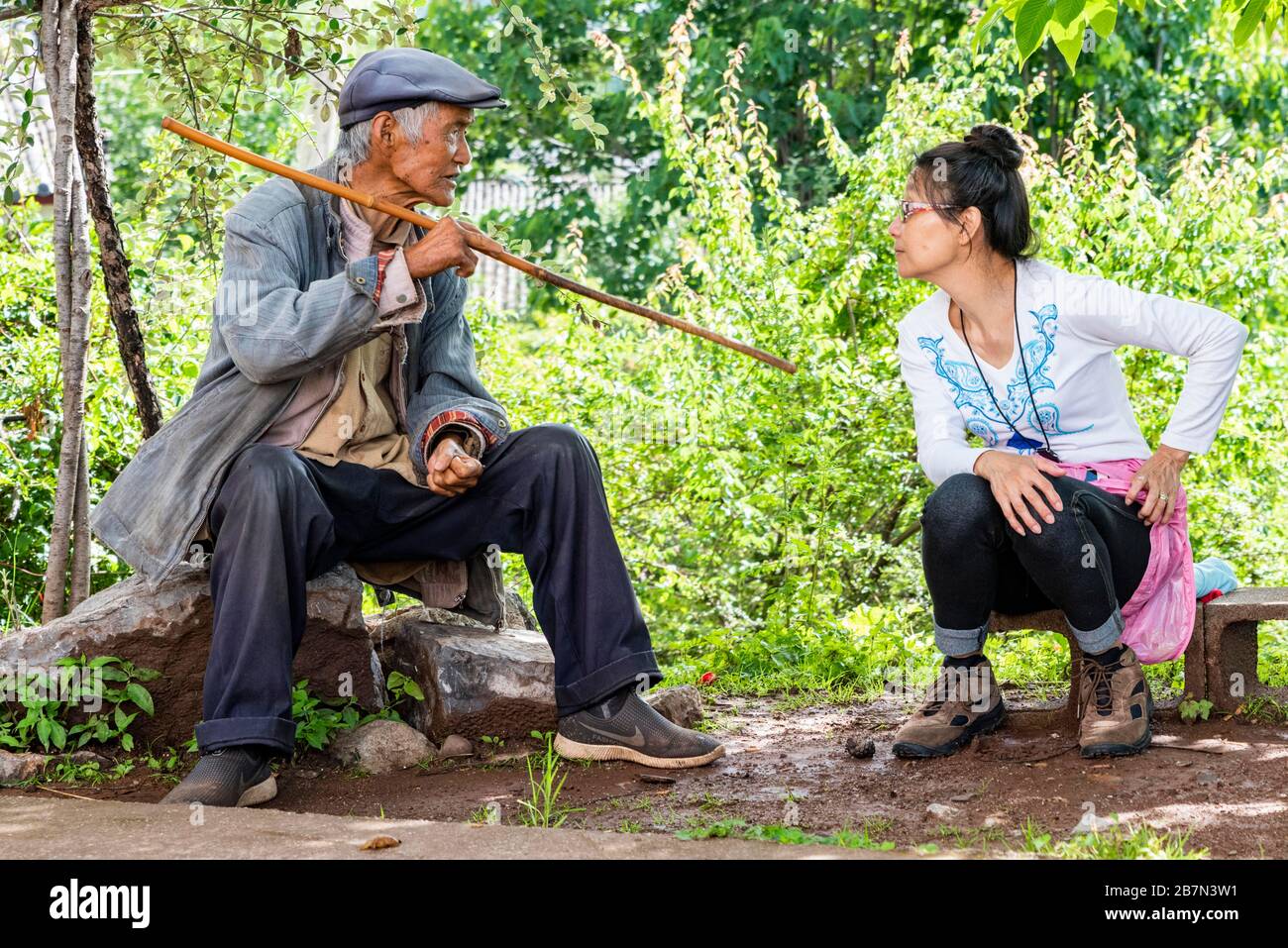 A tourist talking with one of the Naxi people in a section of the Ancient Tea Horse Road, chamagudao, near Lashi Lake in Yunnan China. Stock Photo