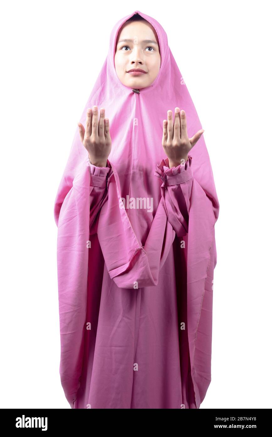 Asian Muslim woman in a veil standing while raised hands and praying ...