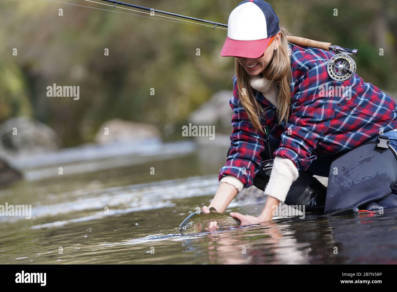 Woman fly fishing river in waders and fishing vest USA Stock Photo