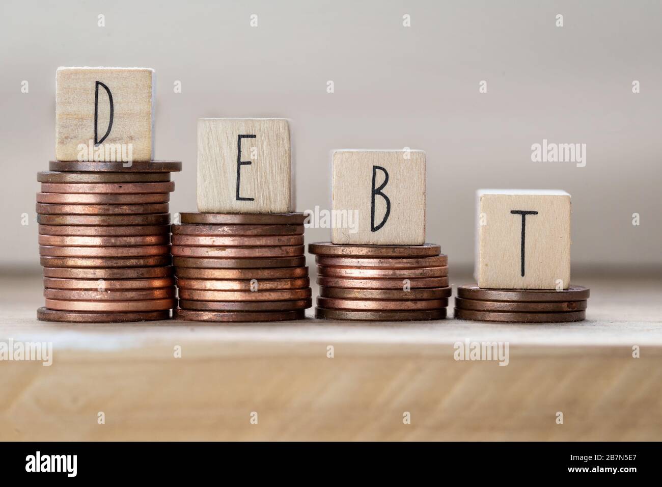 Debt written on wooden cubes with letters, money piles of coins, money climbing stairs wooden background, business concept Stock Photo