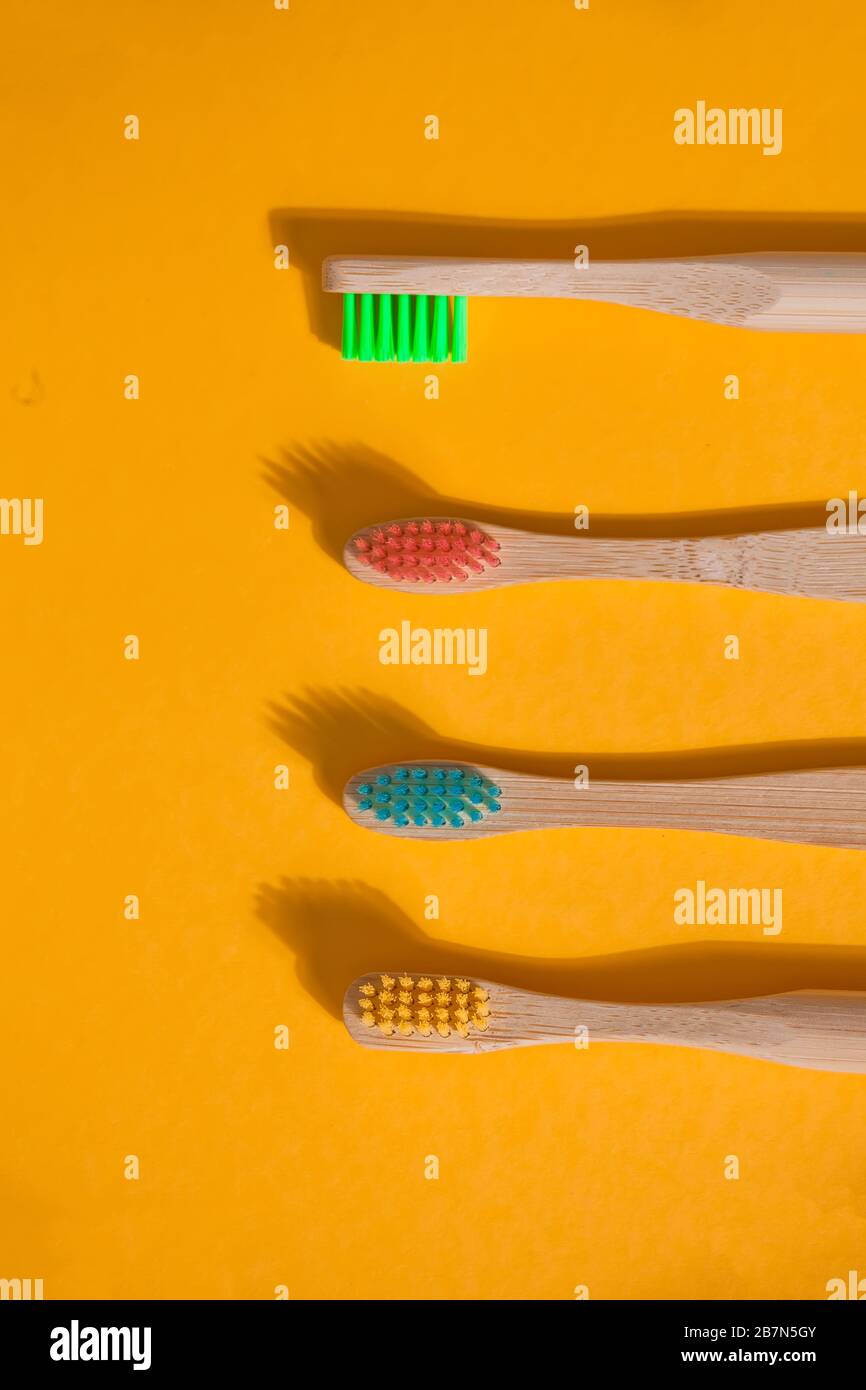 Four eco bamboo kid colorful toothbrushes on the yellow background ...