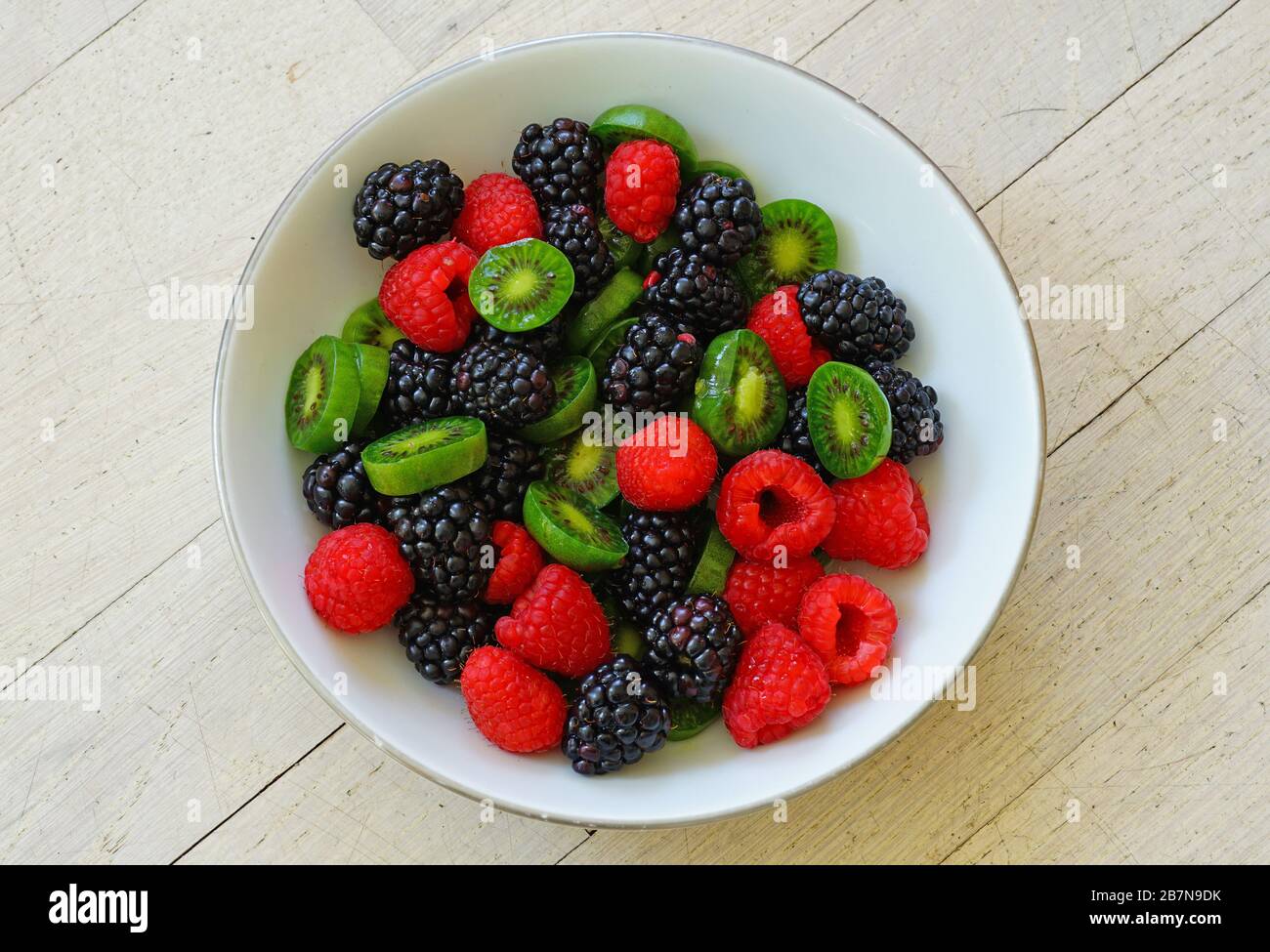 Bowl of fresh sliced baby kiwi fruit, raspberries and blackberries