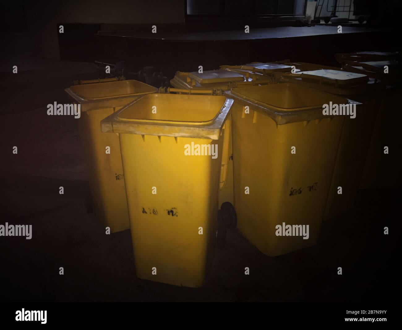 Garbage bin Yellow plastic bin trash at night time Stock Photo