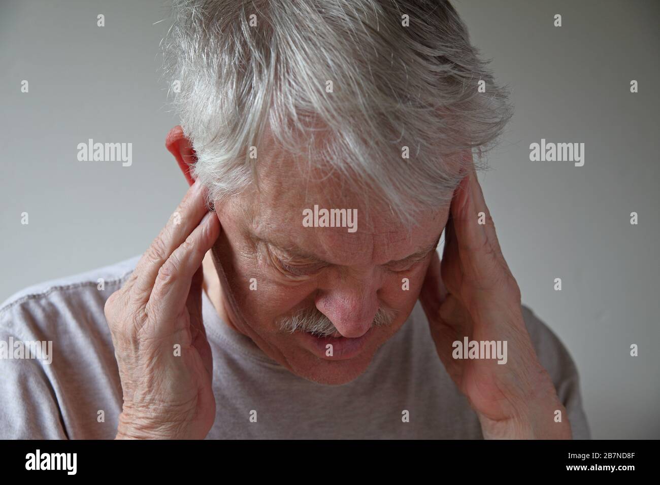 Older man with hands on head looking down Stock Photo