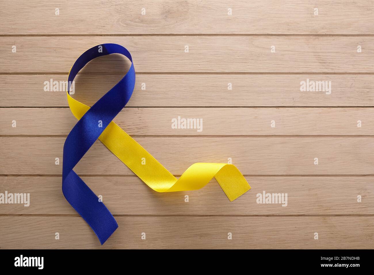 Blue and yellow ribbon on wooden background. World down syndrome day ...
