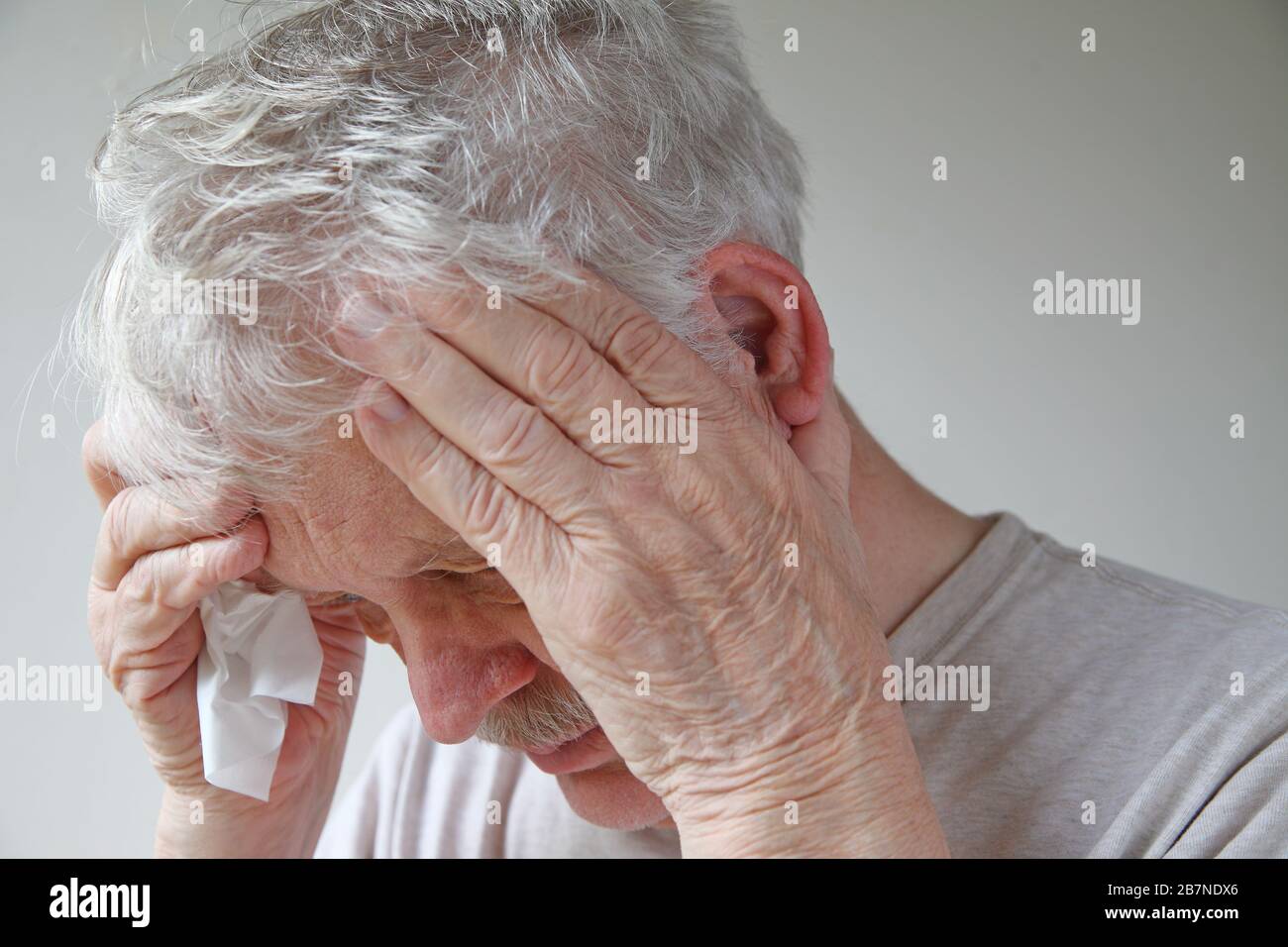 Senior man with tissue holds his feverish head Stock Photo