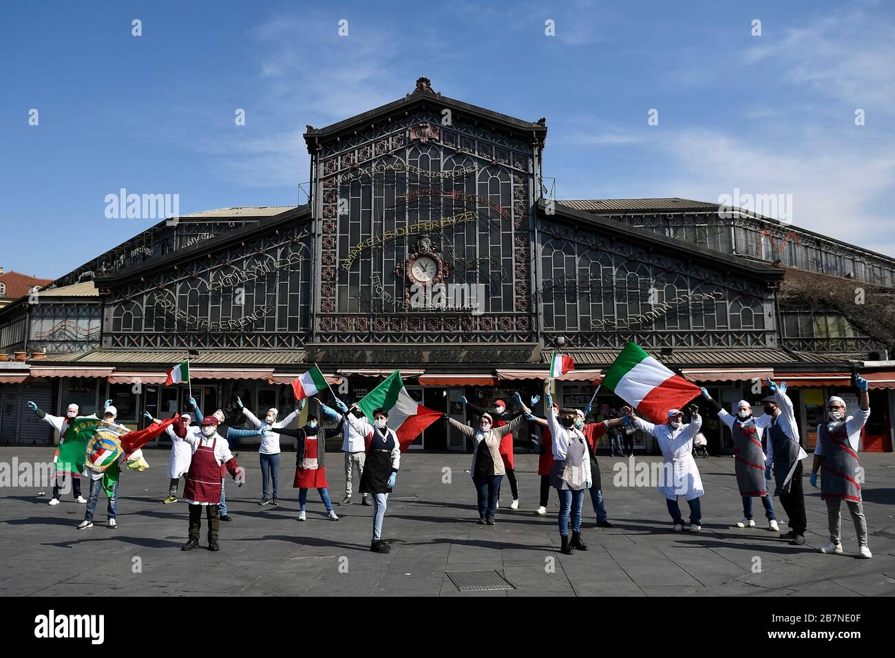 TURIN, ITALY - March 17, 2020: Some merchants from the Porta Palazzo market improvise a flash mob by singing the Italian anthem and waving Italian flags to celebrate the 159th anniversary of the unification of Italy. Merchants stay at a safe distance to comply with measures to prevent the spread of coronavirus. The Italian government imposed unprecedented restrictions to halt the spread of COVID-19 coronavirus outbreak, among other measures people movements are allowed only for work, for buying essential goods and for health reasons. (Photo by Nicolò Campo/Sipa USA) Stock Photo