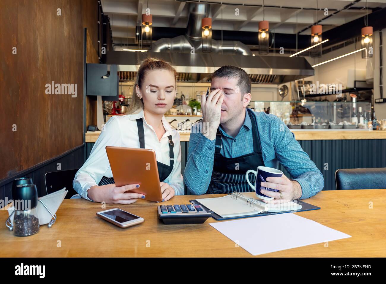 Worried business owners calculating finances - Small restaurant entrepreneurs SME go bankrupt due to Coronavirus pandemic - Young woman and man with h Stock Photo