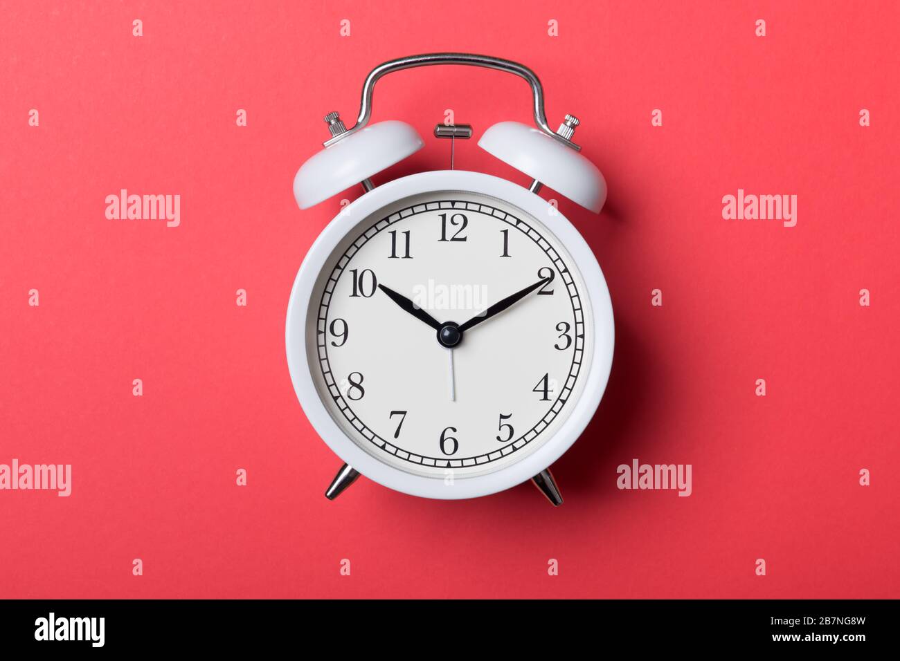 White vintage alarm clock on red background. Time concept Stock Photo