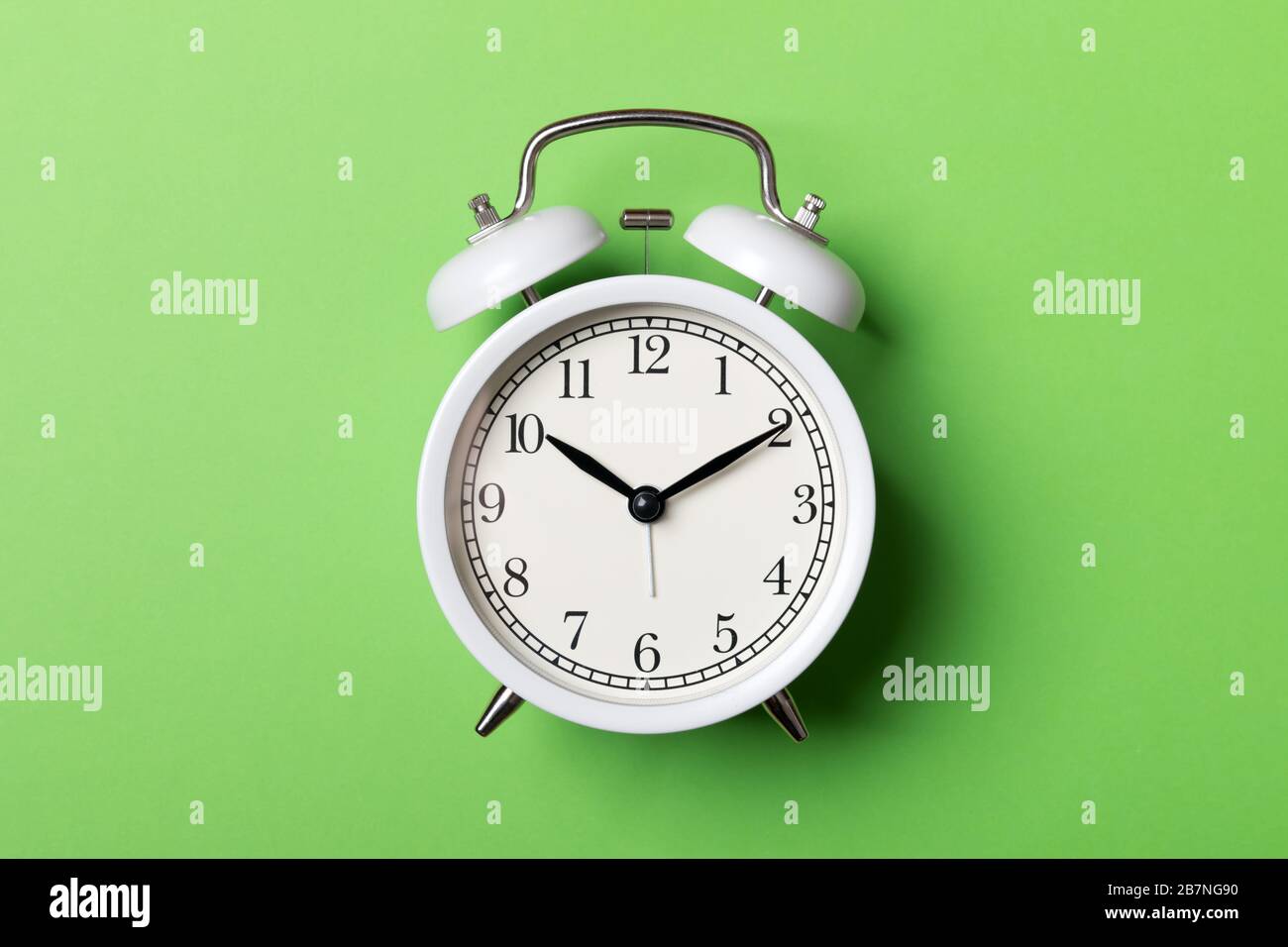White vintage alarm clock on green background. Time concept Stock Photo ...
