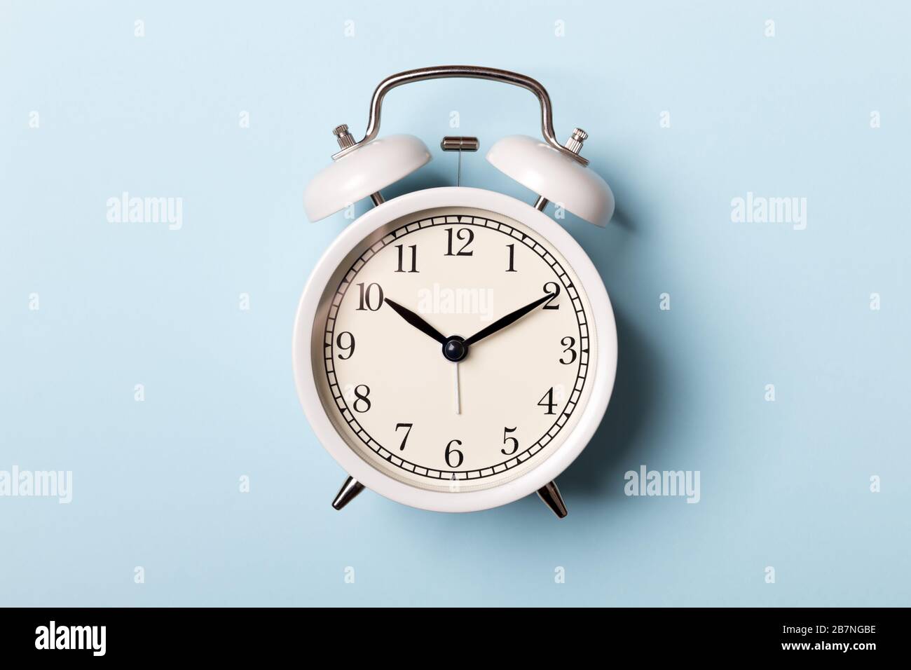 White vintage alarm clock on blue background. Time concept Stock Photo