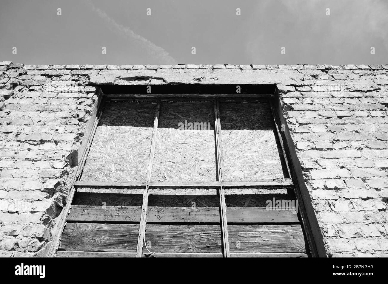 Low angle greyscale shot of an old concrete building with a broken ...