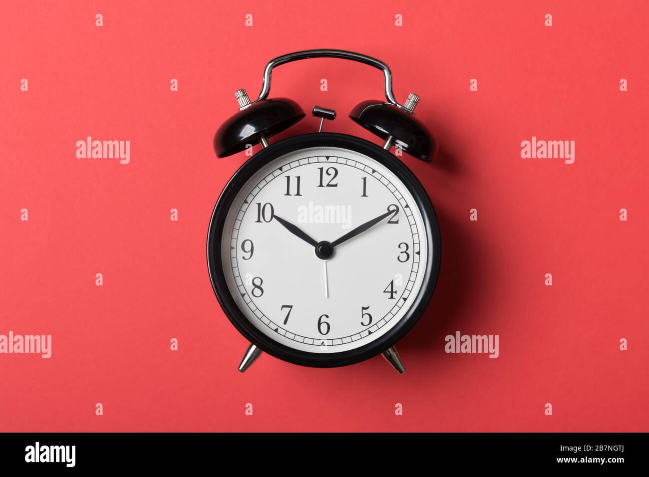 Black vintage alarm clock on red background. Time concept Stock Photo