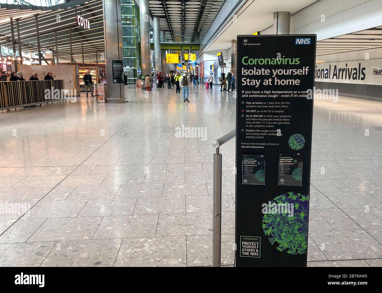 A sign in the empty arrivals area of Terminal 5 of Heathrow Airport telling passengers what to do with Coronavirus as Britons have been advised against non-essential travel to anywhere in the world as the coronavirus crisis closed borders around the globe. Stock Photo