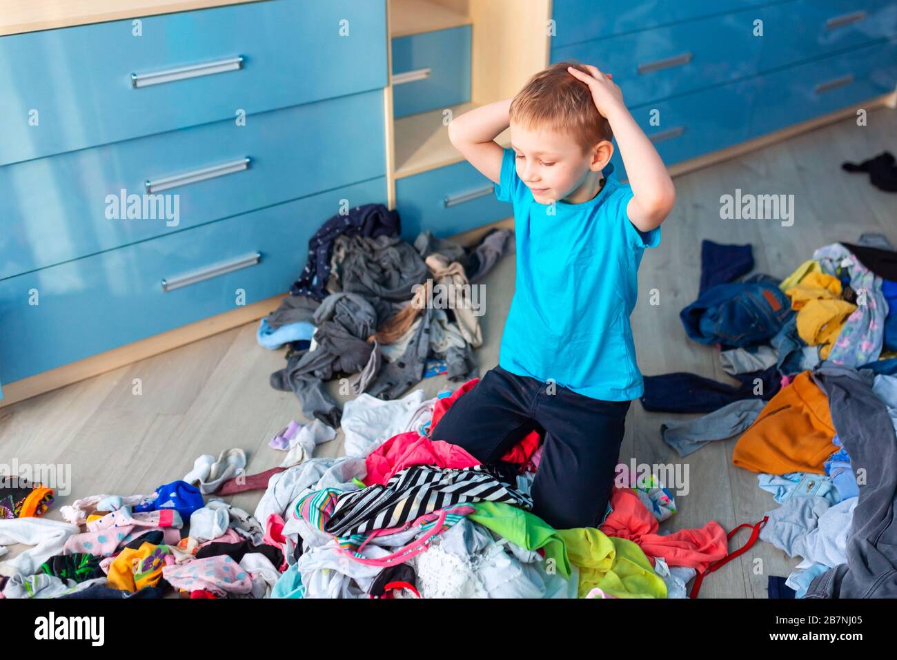 Small boy desperate with the mess in his clothes in his bedroom. Stock Photo