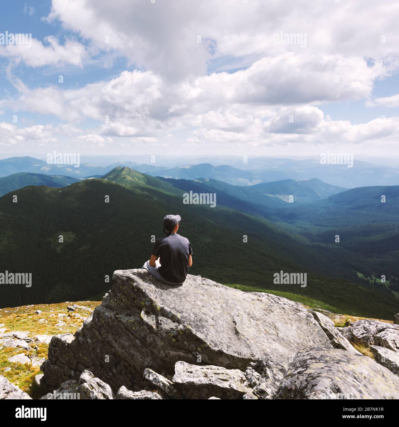 Alone tourist sitting on the rock in high mountains. Landscape photography Stock Photo