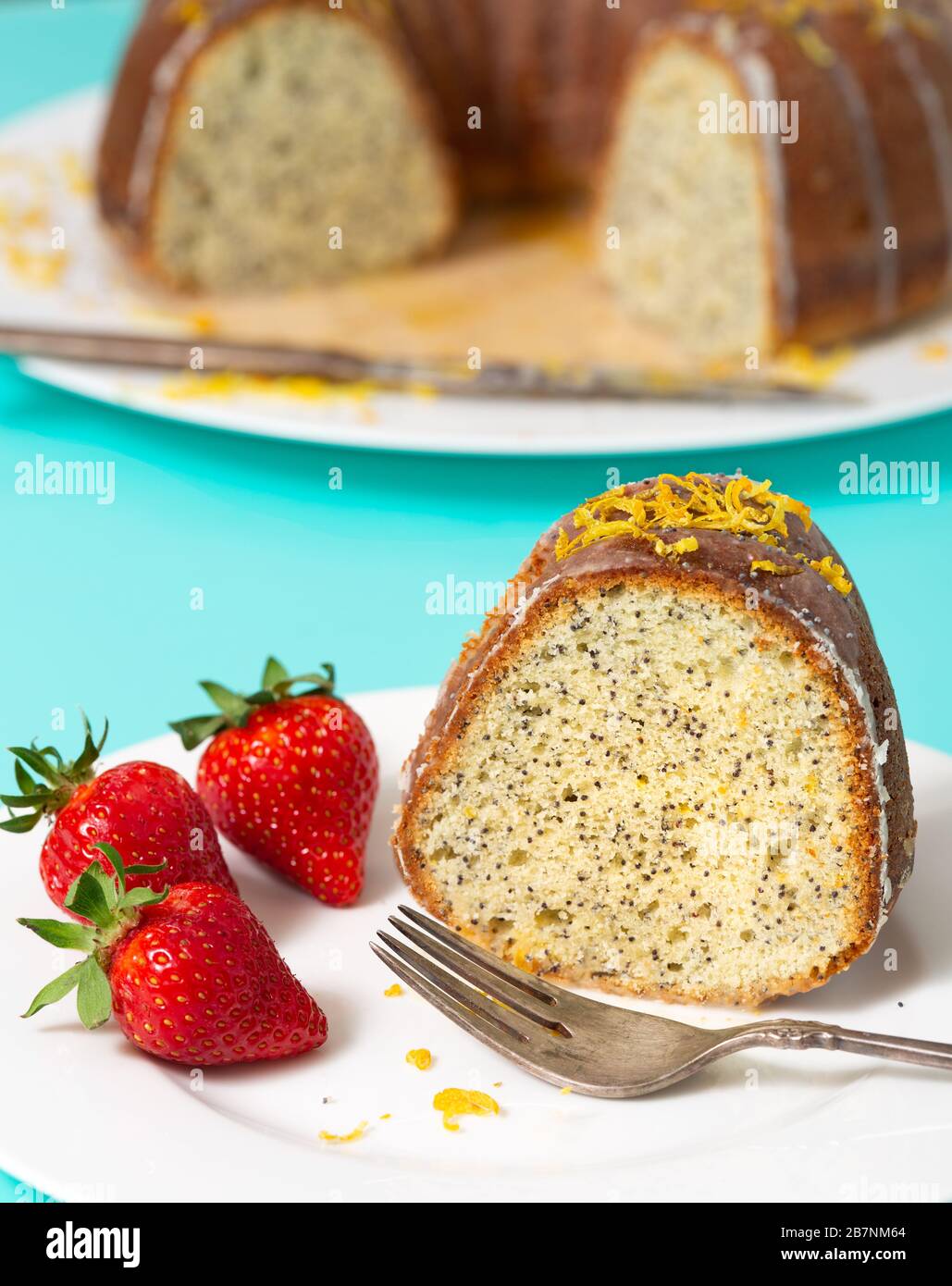 Close-up view of a slice of lemon poppyseed cake served with fresh ripe strawberries Stock Photo