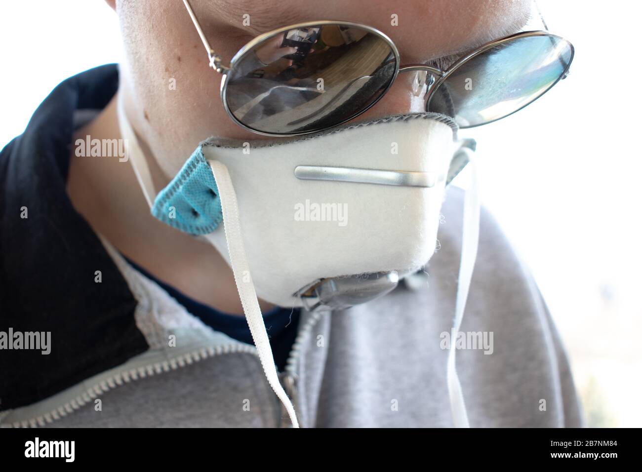 Man in a medical face mask respirator and glasses looks down. Close-up Stock Photo
