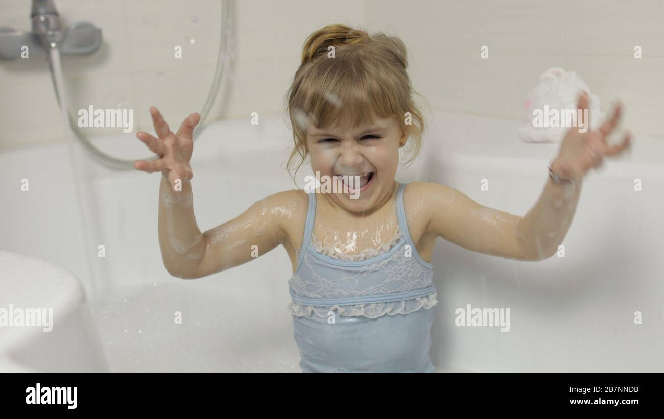 Attractive four years old girl takes a bath in swimwear. Hygiene for