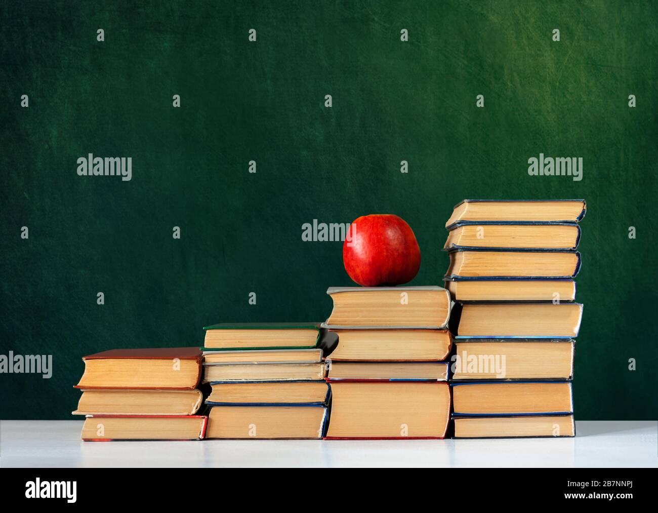 Back to school, pile of books and red apple with empty green school ...