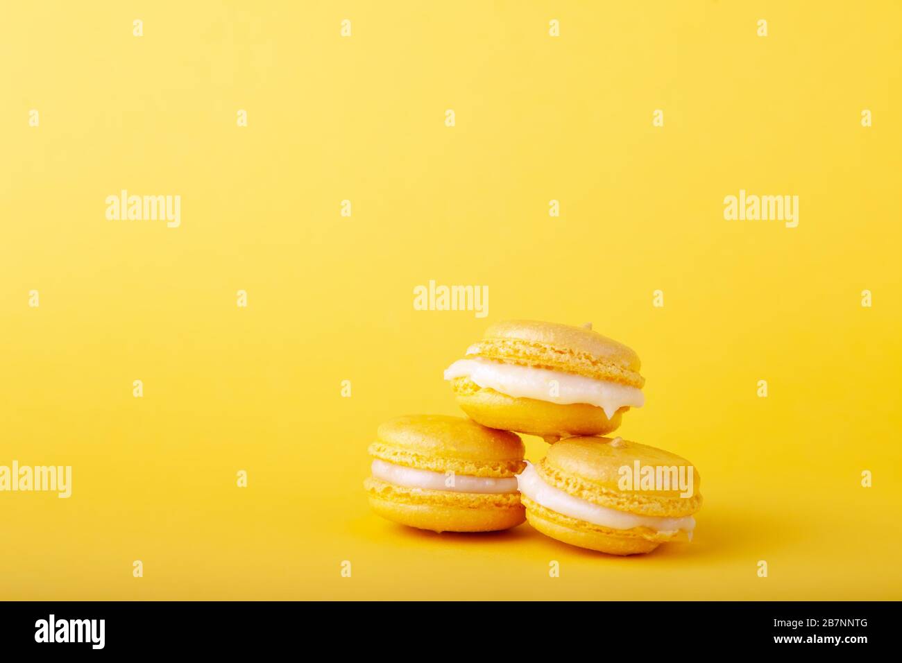 Three yellow lemon macaroon in stack on yellow background, close-up, place for text, copy space, horizontal Stock Photo