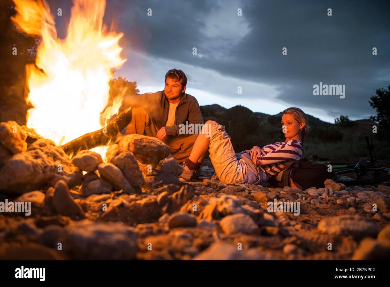 Content young couple sitting by a glowing campfire Stock Photo - Alamy