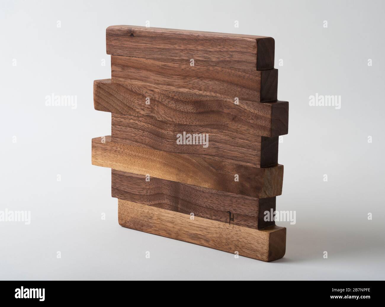 A handmade wooden trivet from walnut for use on a dining table under hot dishes. Stock Photo