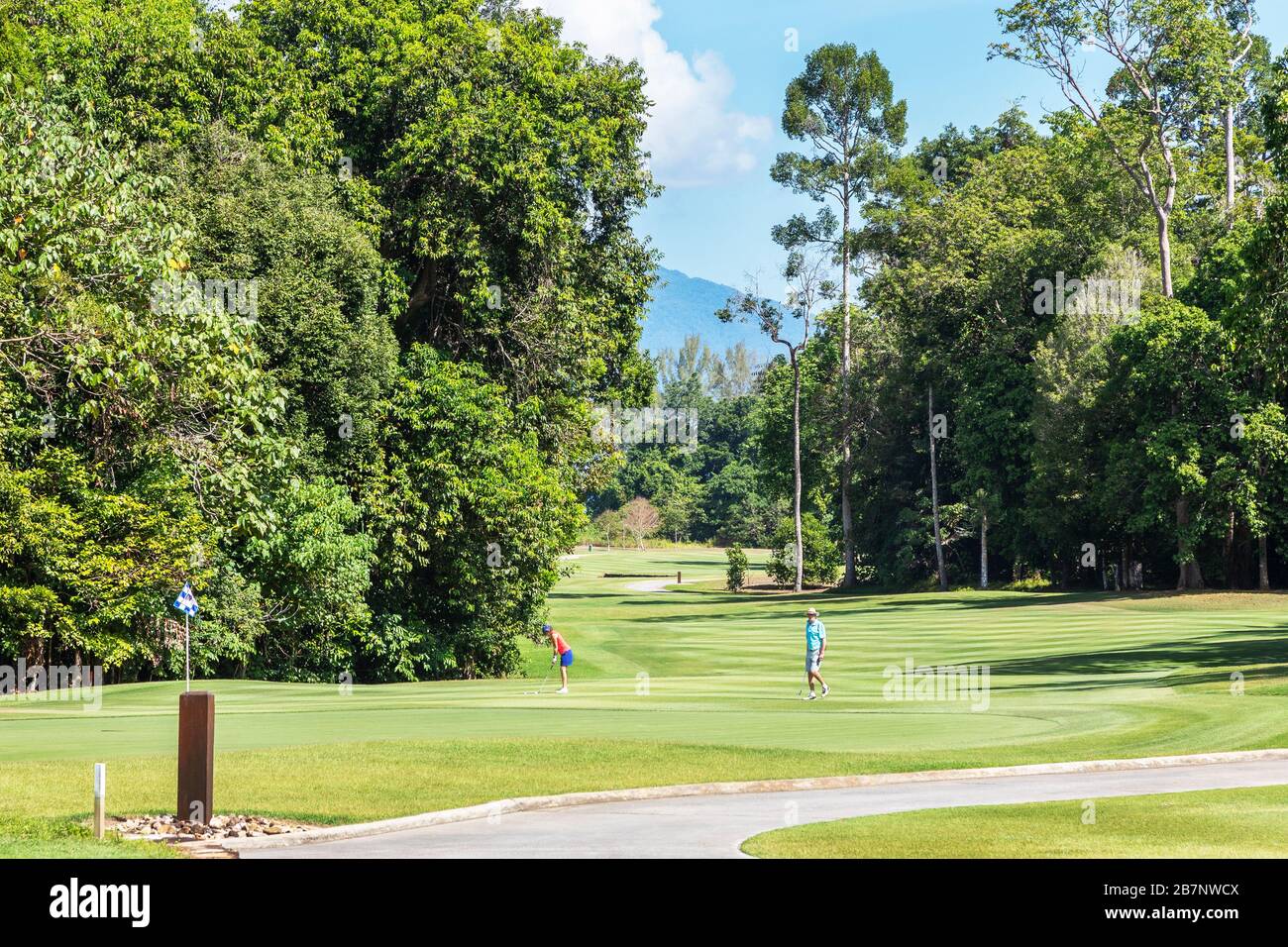 Golfers on the 18th green and a view along the 18th fairway to the Strait of Malaca, The Rainforest club, The Els Club, Teluk Datai,  Malaysia Stock Photo