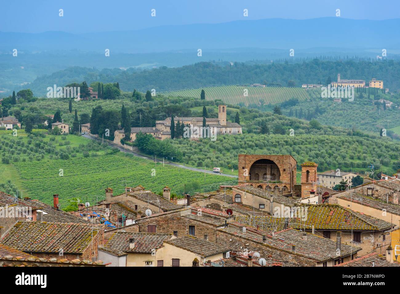 Rooftops of San Gimignano, Tuscan countryside with rolling hills and Santa Maria Assunta a Monte Oliveto Minore from Parco della Rocca, San Gimignano. Stock Photo