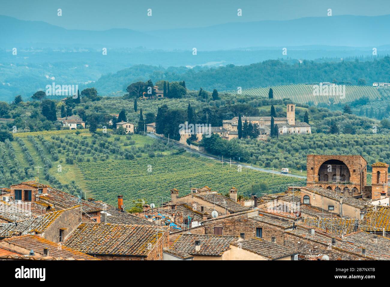 Rooftops of San Gimignano, Tuscan countryside with rolling hills and Santa Maria Assunta a Monte Oliveto Minore from Parco della Rocca, San Gimignano. Stock Photo