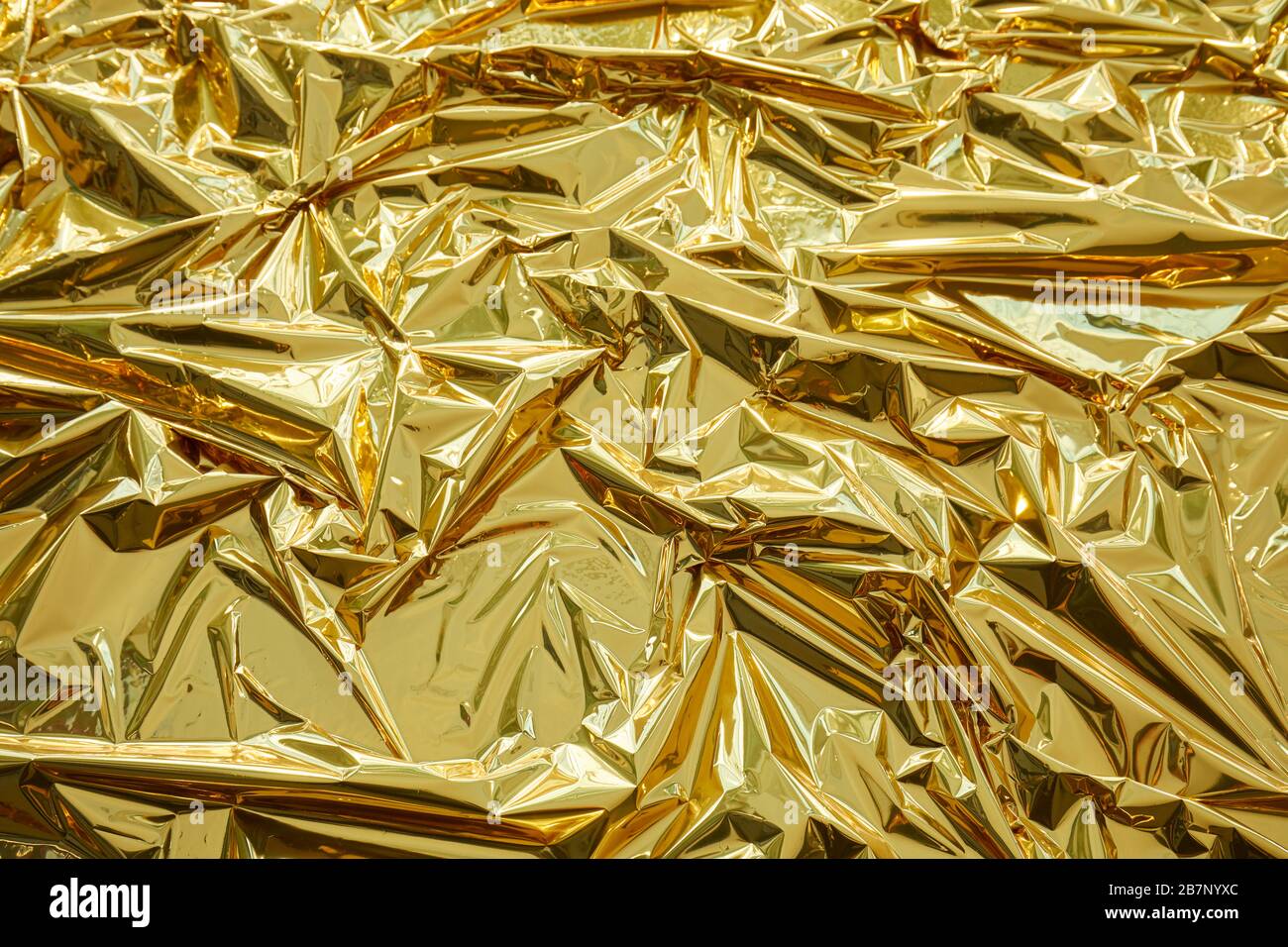 Crumpled, golden metallic foil texture background Stock Photo