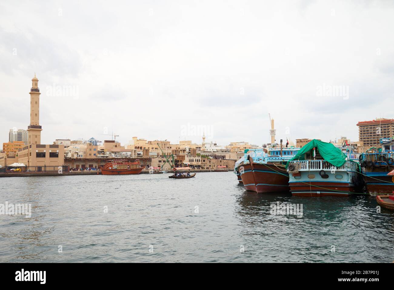 DUBAI, UNITED ARAB EMIRATES - NOVEMBER 21, 2019: Dubai creek, ancient buildings and canal with abra and dhow traditional boats in a cloudy day Stock Photo