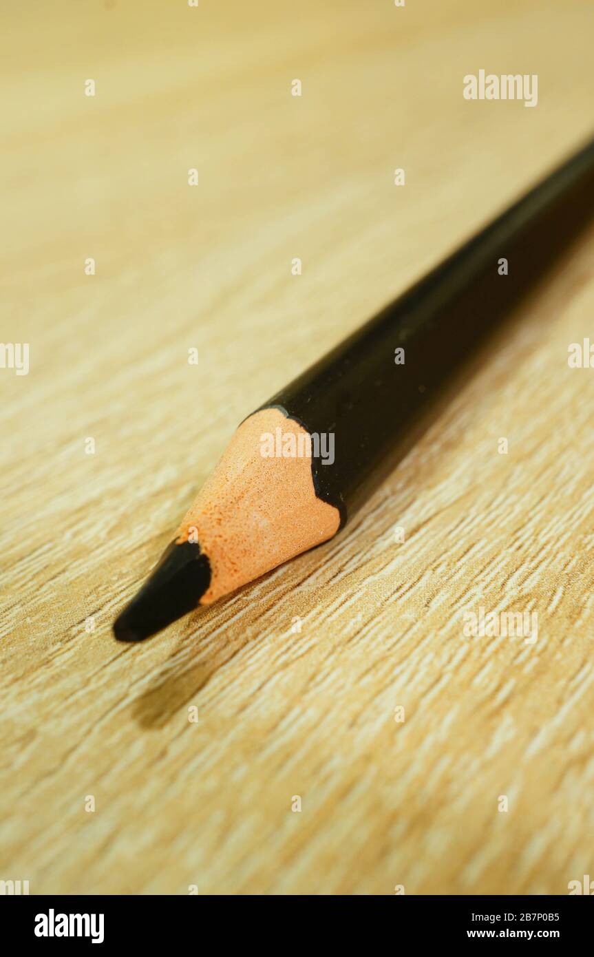 Vertical shot of a black drawing pencil on a wooden surface Stock Photo