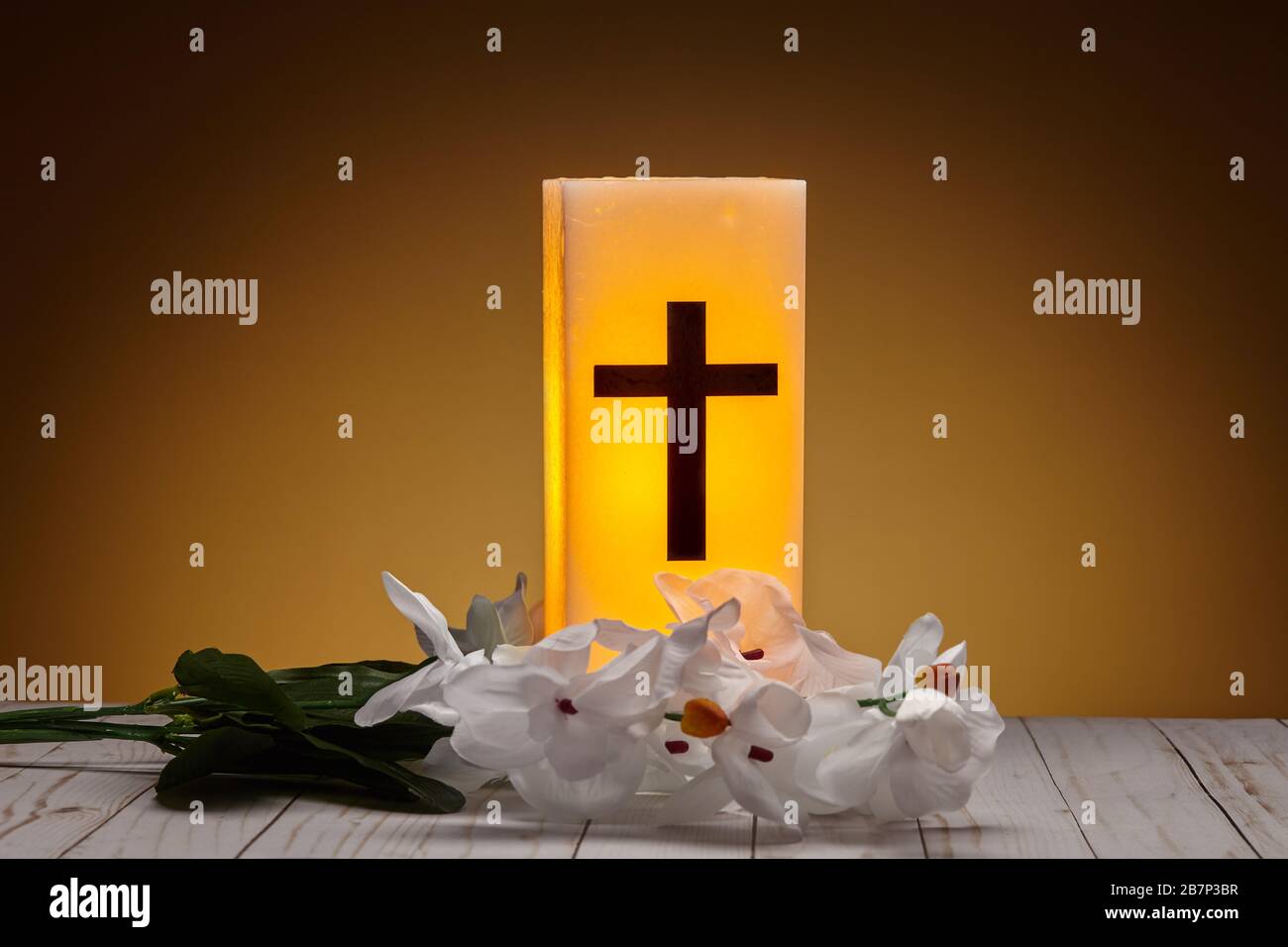 Glowing Yellow Wax Christian Candle With Artificial Flowers Stock Photo