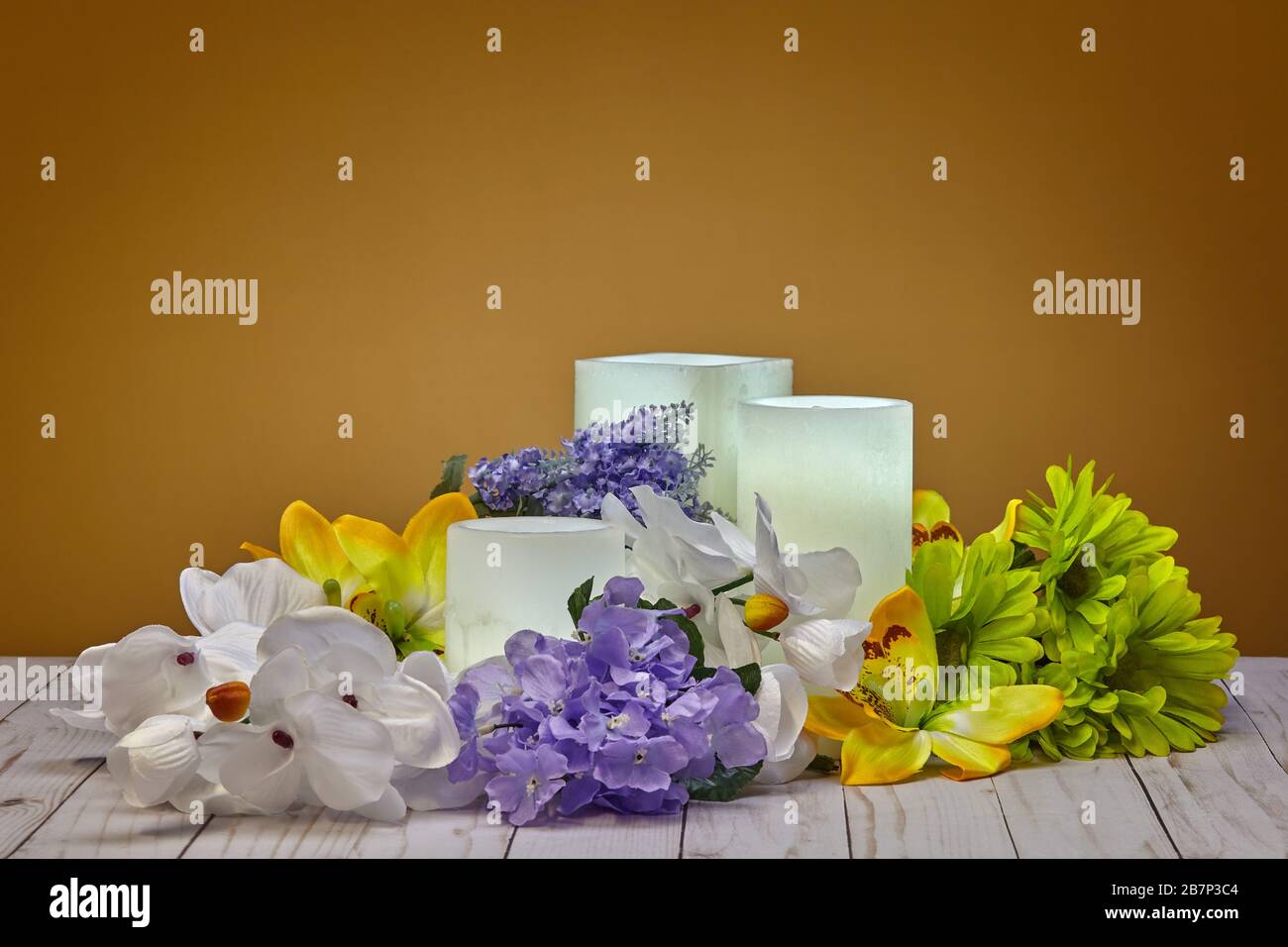 Group of Glowing White Wax Candles and Artificial Spring Flowers Stock Photo