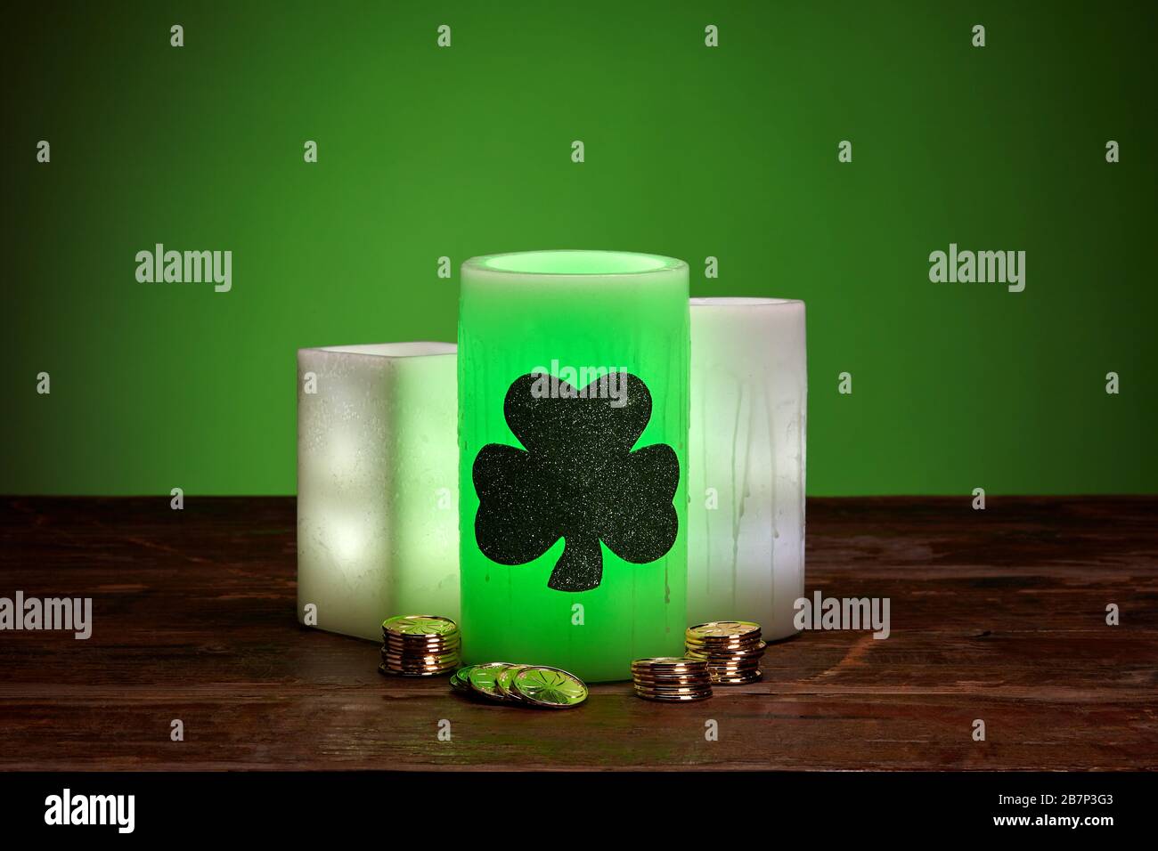 Glowing green wax candles and stacks of gold coins for St. Patrick's Day Celebration Stock Photo