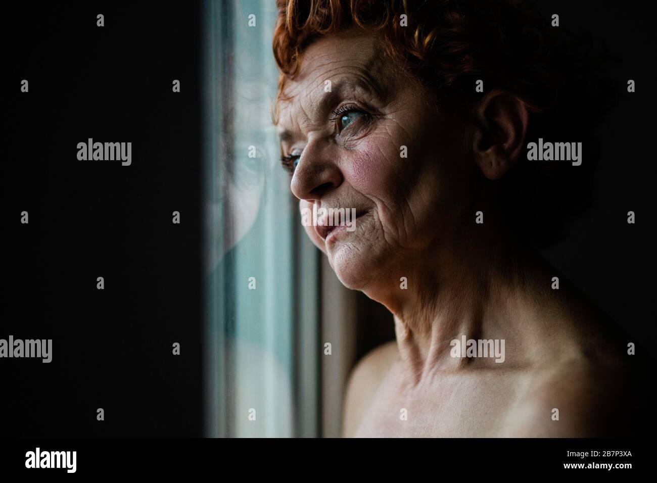 Mature woman by the window thinking about life Stock Photo